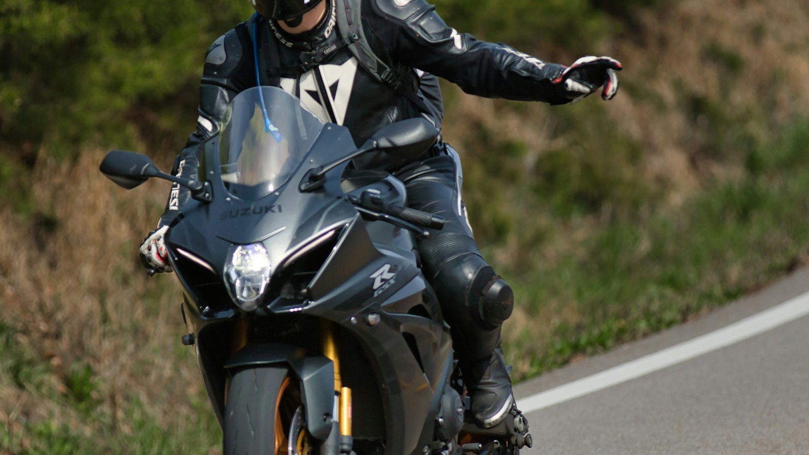 Motociclist oprit pe o culme din Carpați, cu motocicleta de aventură alături și valuri de dealuri împădurite în depărtare
